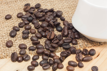 Coffee beans on sackcloth and wood background.