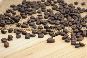 Coffee beans on sackcloth and wood background.