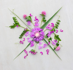 a bouquet of various purple flowers with green leaves on grey background. Flat lay, top view