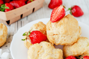 
dessert with berries , custard eclairs or cakes with cream and red strawberries on a wooden background