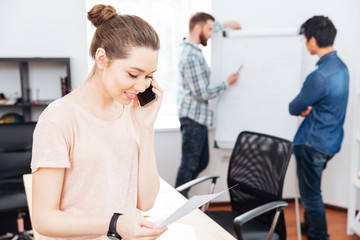 Cheerful businesswoman talking on mobile phone in office