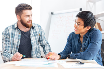 Two happy young businessmen working together in office