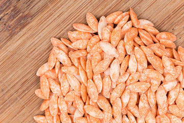 Pile of red hybrid cucumber seeds on the wooden board