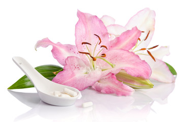 Two pink lily flowers with pills. Isolated on white background