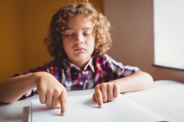 Naklejka premium Boy using braille to read