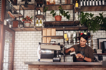 Young male barista making a cup of coffee - obrazy, fototapety, plakaty