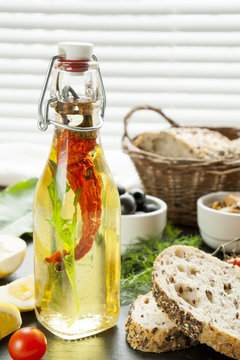 Bottle of olive oil with spices and bread, mussels and black olives and in ceramic bowls, fresh tomatoes, sliced lemon on black stone board. Mediterranean food on black stone board