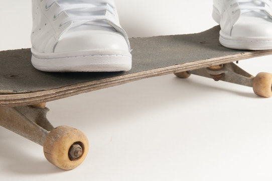 Mans feet standing on an old skateboard
