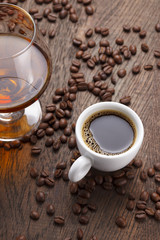 Cup of coffee, cognac glass and coffee beans on a wooden table