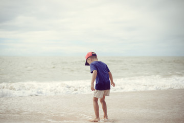 Back view of little boy walking along the beach during the sunset