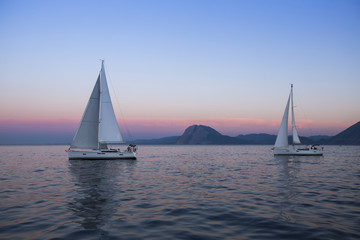 Sail boats near the rocky shores after amazing sunset.