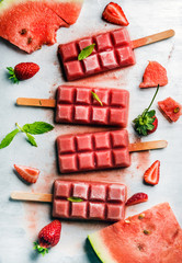 Strawberry watermelon ice cream popsicles with mint over steel tray background