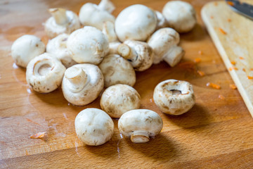 Whole Fresh White Mushrooms on Wooden Board.