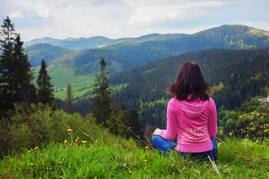 young girl sitting on top and looks at mountain