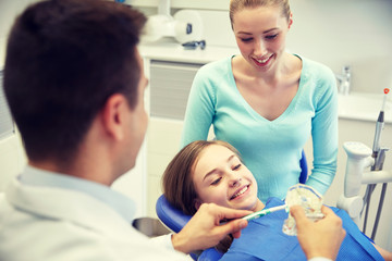 Obraz na płótnie Canvas happy dentist showing toothbrush to patient girl