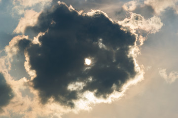 Fototapeta na wymiar Sun trying to brake trough a dark storm cloud at sundown