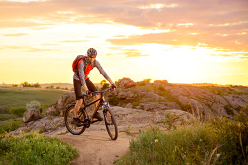 Fototapeta na wymiar Cyclist Riding the Bike on Mountain Rocky Trail at Sunset