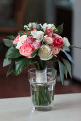 beautiful bridal bouquet standing in a glass on a wooden table, wedding bouquet of roses, freesias and carnations