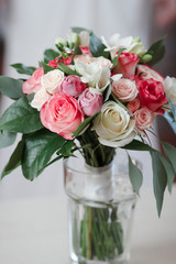 beautiful bridal bouquet standing in a glass on a wooden table, wedding bouquet of roses, freesias and carnations