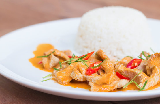 Red pork curry (Panang) with rice in white plate on wooden backg