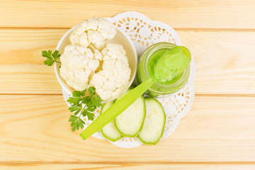 Jar  baby puree  cauliflower, zucchini on  background  light wood.