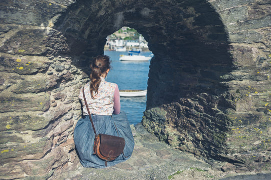 Young woman relaxing under stone wall arch