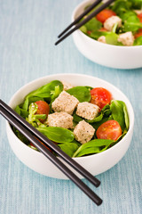 Vegan tofu salad in bowl with tomatoes and lamb's lettuce
