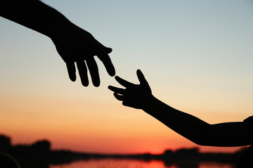 silhouette parent holds the hand of achild