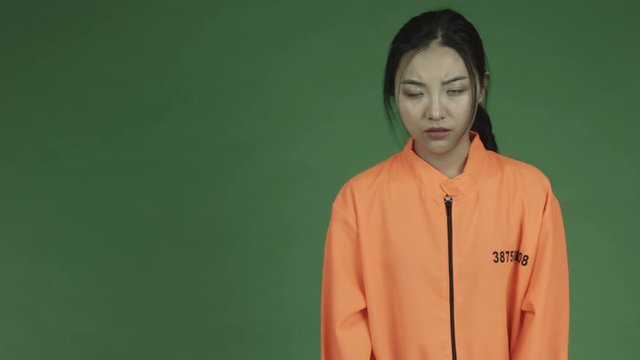 young asian adult woman prisoner isolated on green-screen background worried handcuffs