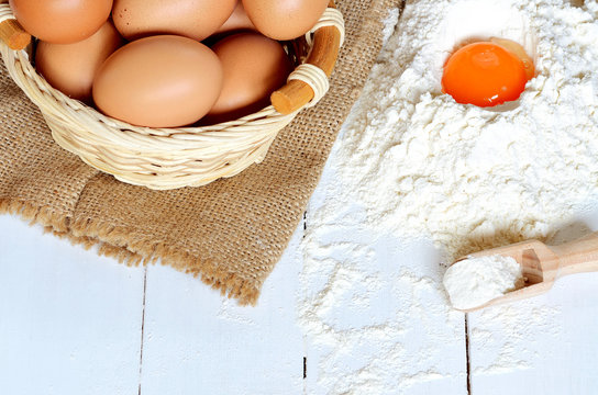Eggs, flour and yolk on white desk