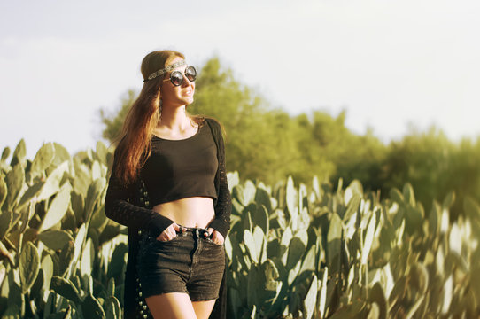 Young female in hippie clothes, sunglasses and headband standing