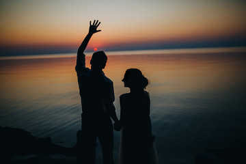 Fototapeta premium man and woman sitting at sunset on a wooden quay on a lake in the woods