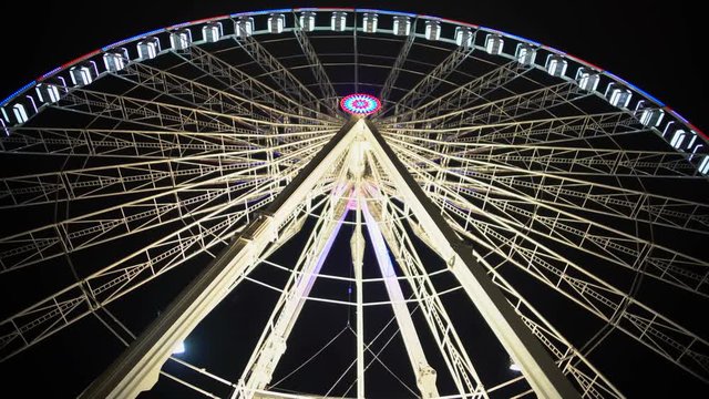Gigantic Ferris wheel rotating slowly at theme park against back sky background