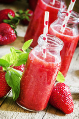 Sweet strawberry cocktail with sugar, mint and straws in glass b