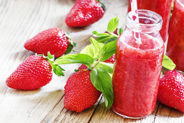 Sweet strawberry cocktail with sugar, mint and straws in glass b