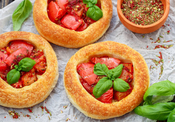 Homemade pie of puff pastry with tomatoes, Basil and spices. Mini round tomato tart. Rustic style
