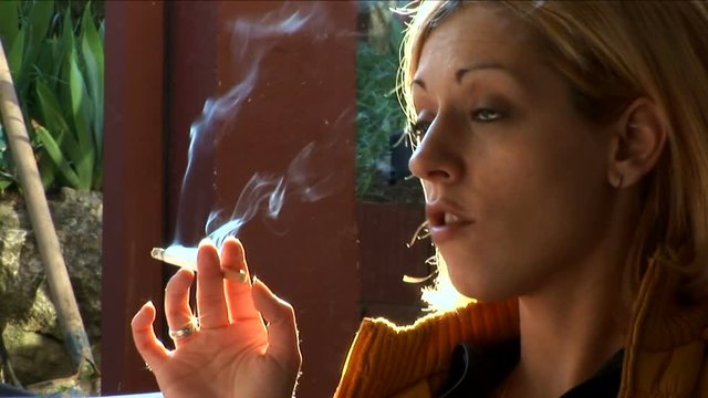Blonde woman smoking outdoors 