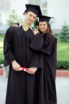 Classmates in clothes of graduates are embracing