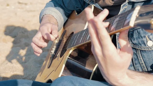 Man playing guitar on the beach, slow motion