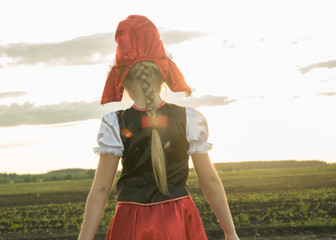 little girl dressed as Little Red Riding Hood in the spring forest