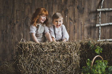 Children play among the bales of hay on the background of wooden © alenazamotaeva