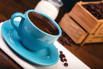 Cup of coffee and wooden containers filled with cofee beans