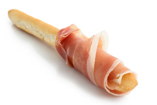 Prosciutto ham rolled onto grissini bread stick. Isolated on whi - Powered by Adobe