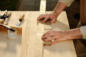 Carpenter at work arranging pieces of wood on table