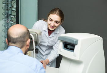 female ophthalmologist and mature patient checking eyesight in c