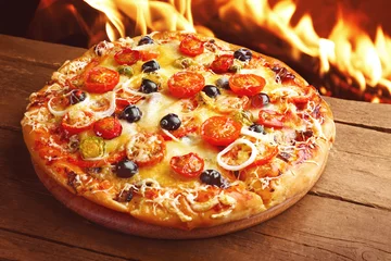 Foto op Plexiglas Delicious hot pizza on wooden table against fire flame background © Africa Studio