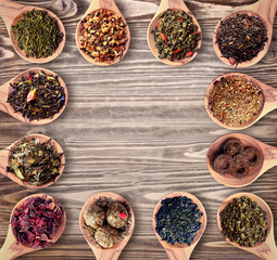 Set of different tea in wooden spoons on wooden background