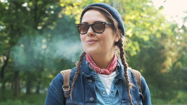 Portrait of young woman smoking in park, slow motion