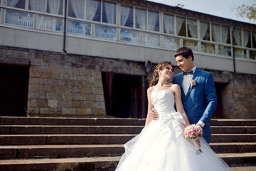 Wedding couple on the nature is hugging each other. Beautiful model girl in white dress. Man in suit. Beauty bride with groom. Female and male portrait. Woman with lace veil. Lady and guy outdoors