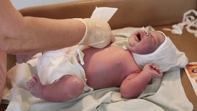 Nurse in gloves swaddle newborn crying baby in diapers in maternity hospital. Medical. Child. White cap